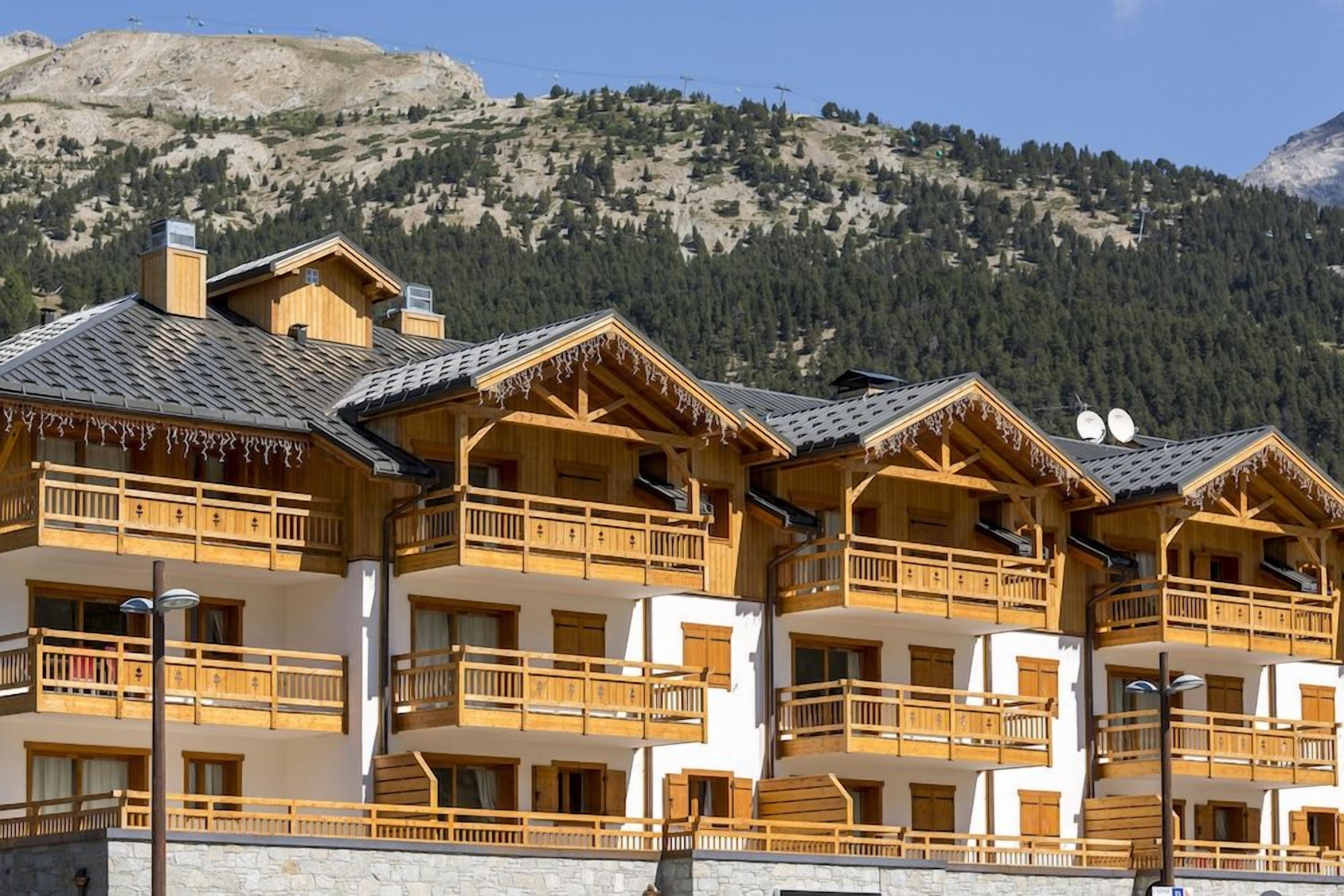 File di chalet in legno con balconi, con montagne sullo sfondo.