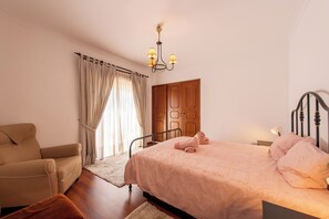 A bedroom with a bed, a chair, a wooden wardrobe, and a chandelier. - 340 m2 Romantic Portugal independent house 5 min. from the sand beach and ocean. (Cascais)