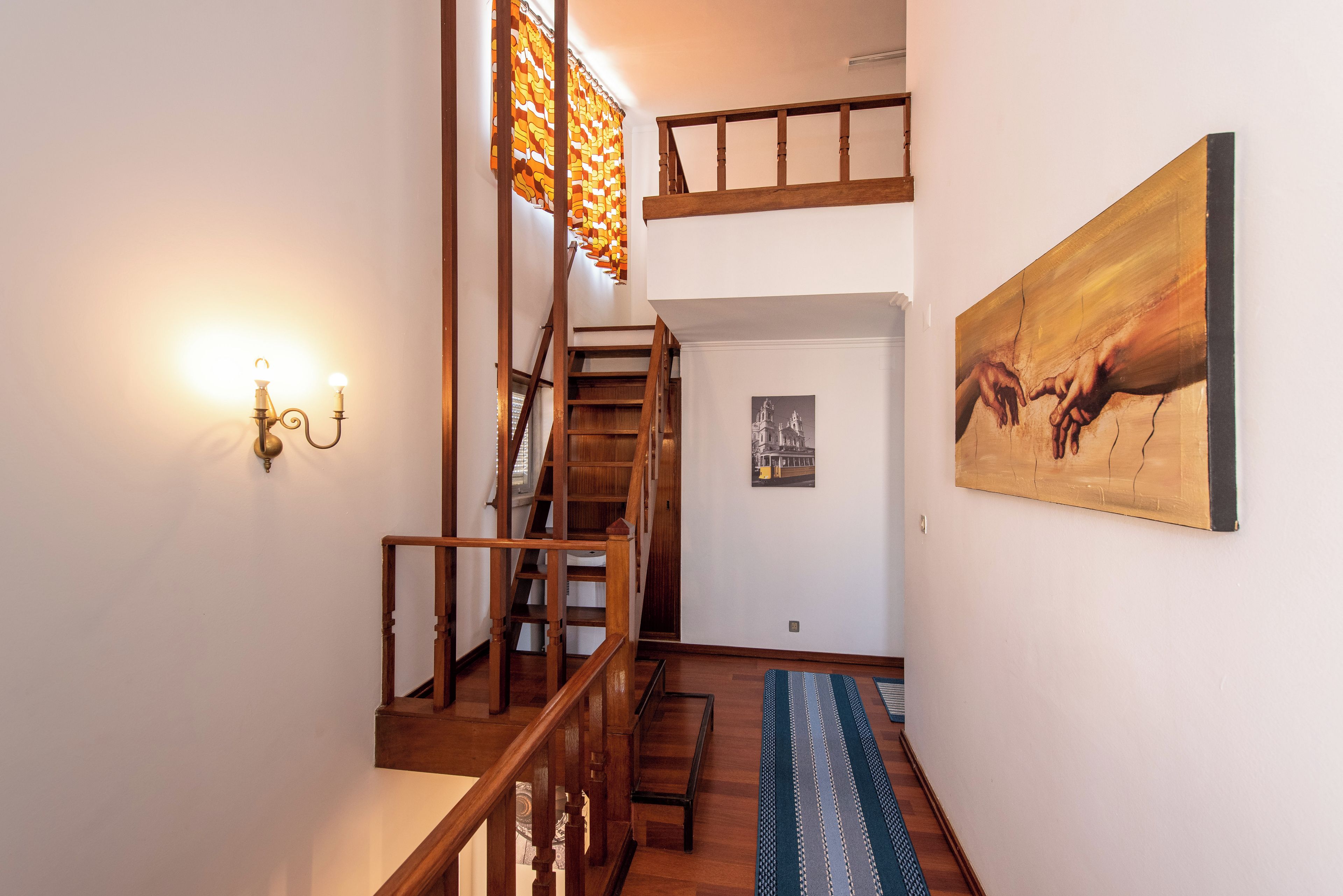 Una scala con ringhiere in legno, un lampadario a parete e un quadro.