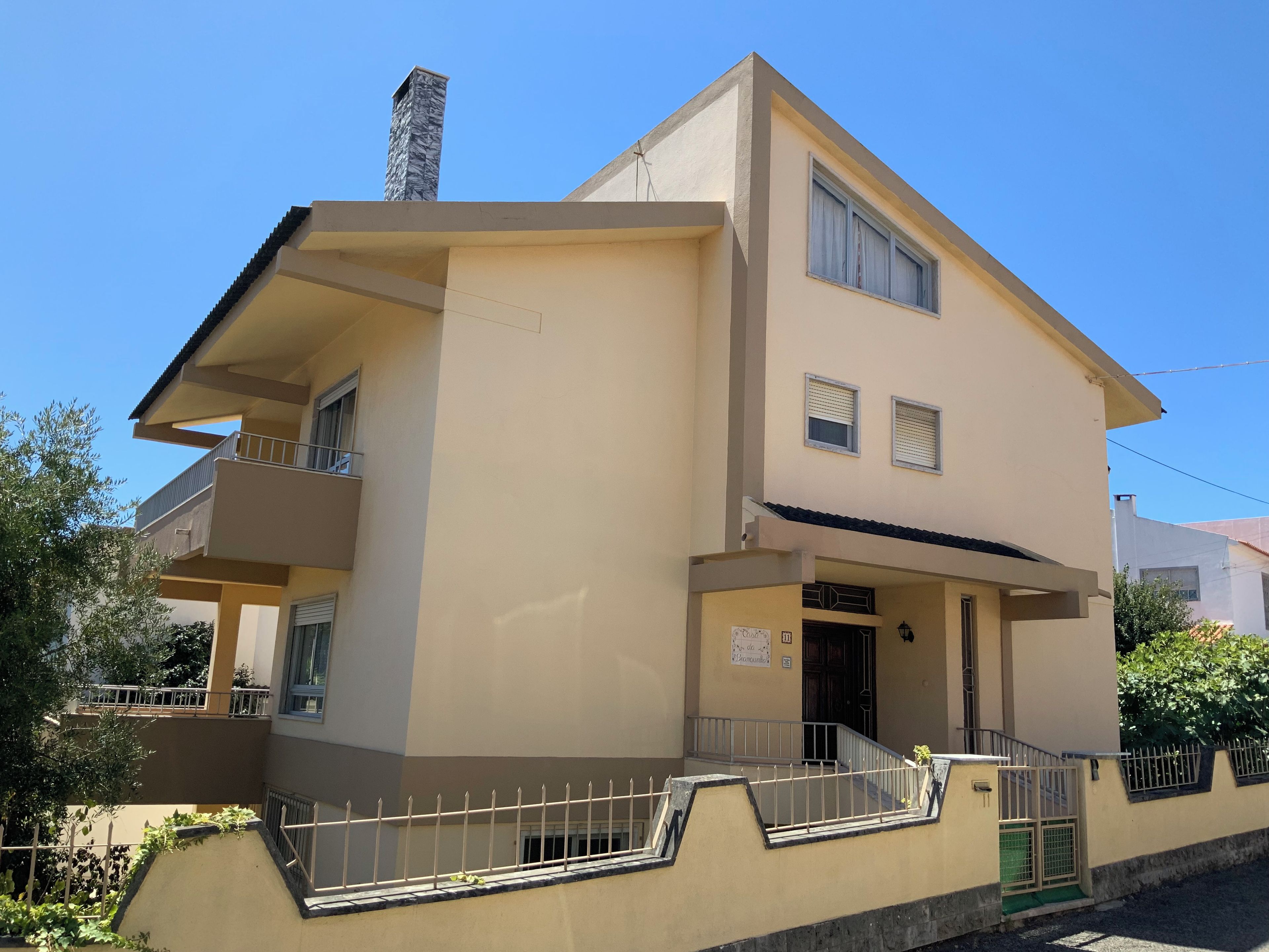 A two-story building with a balcony, a chimney, and a gated entrance.
