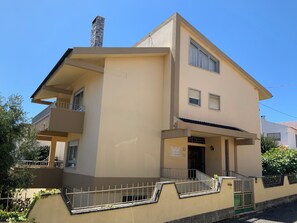 A two-story building with a balcony, a chimney, and a gated entrance.