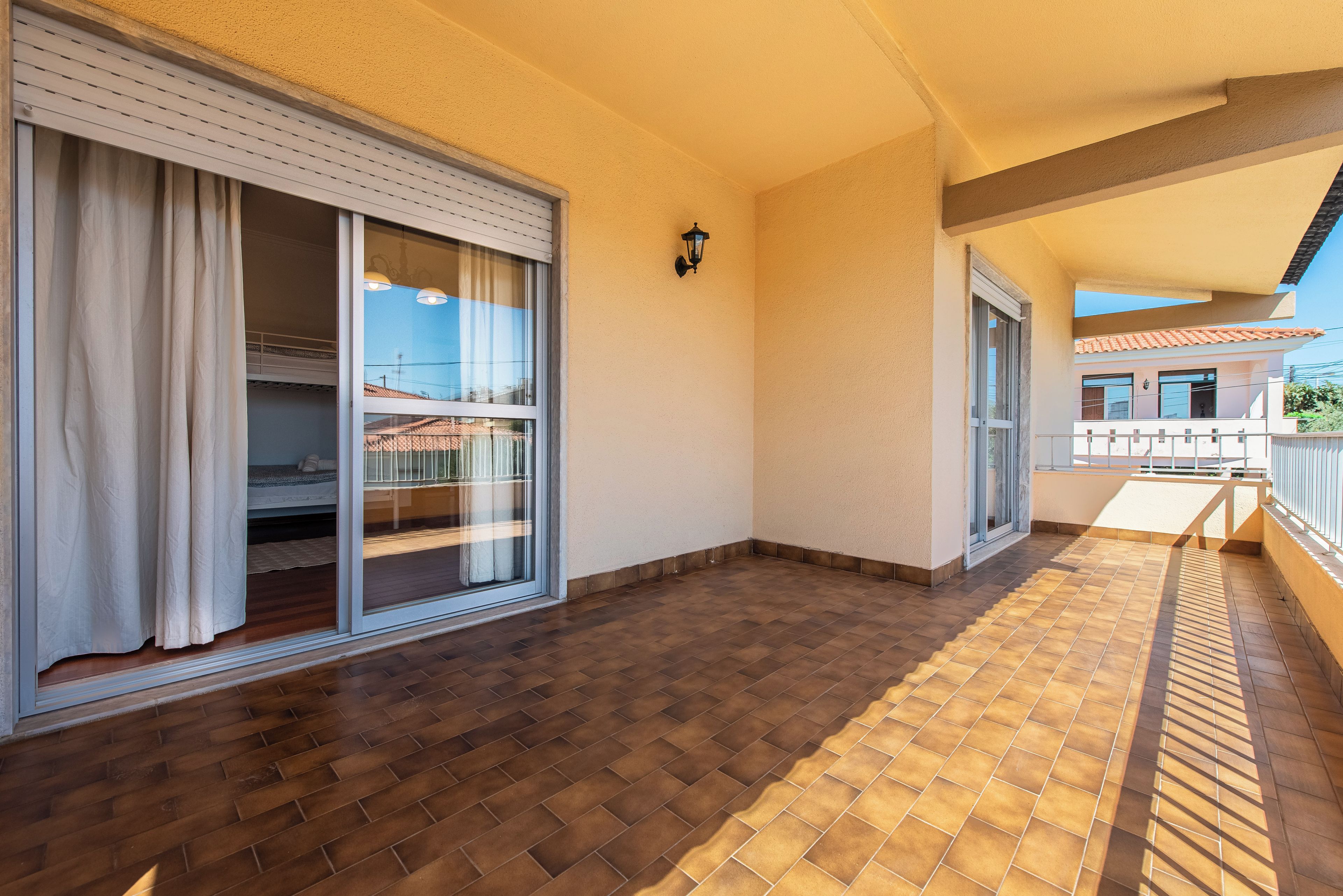 Un balcon doté d’un sol carrelé, d’une porte-fenêtre coulissante et d’un petit espace aménagé pour s’asseoir à l’extérieur.