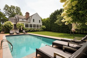 Ein Swimmingpool mit Liegestühlen und ein Haus im Hintergrund.