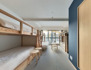 A compact hotel room with bunk beds, a small table, and a view through a large window. - Riverside Hostel Yurariver Susaki (Fukuoka)