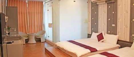 A hotel room with two beds, a desk, a chair, and a small table.