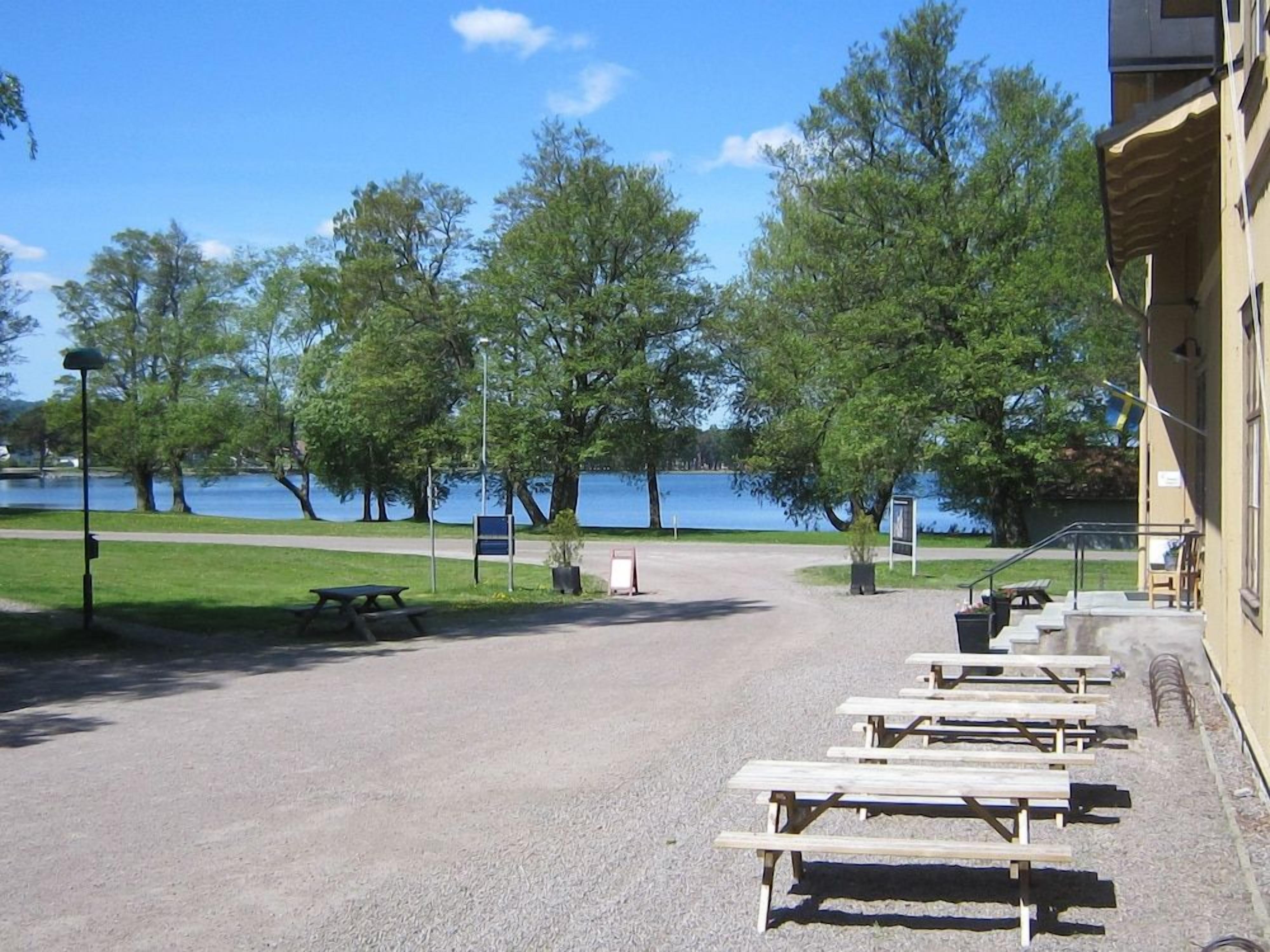 En grusbelagd parkeringsplats med picknickbord och en byggnad på höger sida.