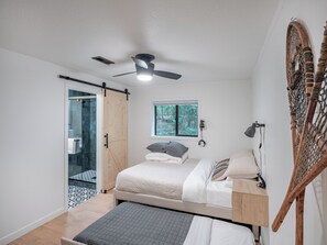 A bedroom with a bed, a ceiling fan, a window, and a wooden headboard. - Riverfront Mt. Hood Retreat with Hot Tub + Game Room (Rhododendron)
