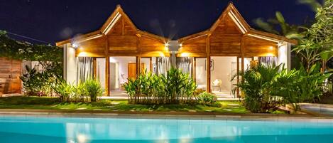 A two-story wooden building with a swimming pool in front.