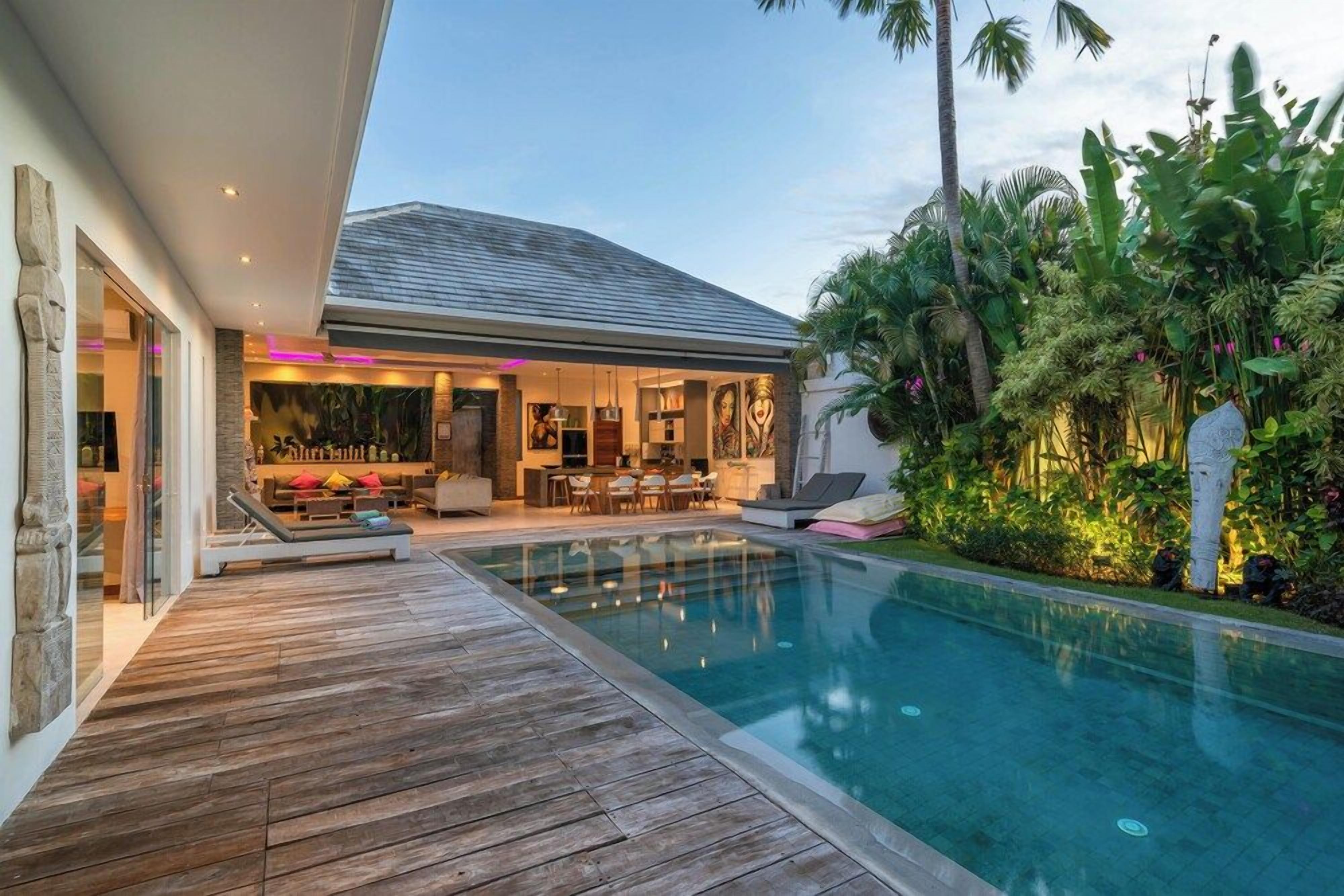 A modern house with a swimming pool, a wooden deck, and a lush garden.