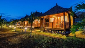 A row of wooden villas with tiled roofs, surrounded by well-maintained gardens and palm trees.