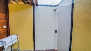 A small, enclosed shower area with tiled walls and a wooden bench.