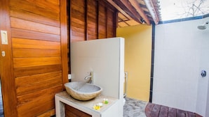 A bathroom with a stone sink, wooden walls, and a shower area.