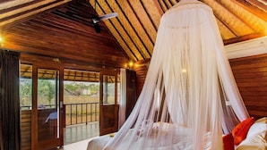 A bedroom with a canopy bed, wooden ceiling beams, and a view of the outdoors.