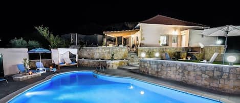 A swimming pool with lounge chairs and a covered patio area.