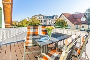 Un balcon avec une table et des chaises, un magazine et un vase rempli de fleurs.