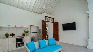 A modern living area with a sofa, kitchenette, and a flat-screen TV. - Villaley Double Six (Legian)