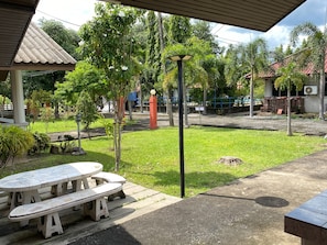 An outdoor seating area with picnic tables, surrounded by greenery and a playground.