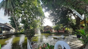 A serene waterway with a swan sculpture, surrounded by lush greenery and traditional architecture. - Chakdaw Mountain View Resort (Nakhon Nayok)