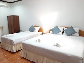 A hotel room with two beds, a wardrobe, a nightstand, and a lamp.