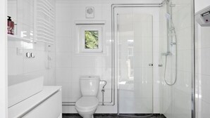 Un baño moderno con inodoro, cabina de ducha y ventana con vistas a zonas verdes.