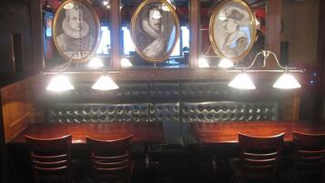 A bar area with a leather booth seating arrangement and framed portraits on the wall.