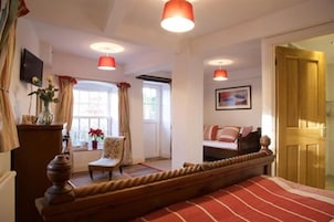 Una habitación con una cama, una silla, un televisor y una ventana con cortinas.