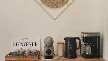 Una kitchenette equipada con cafetera, hervidor de agua, tostadora y un cartel que dice 'BIENVENUE'.