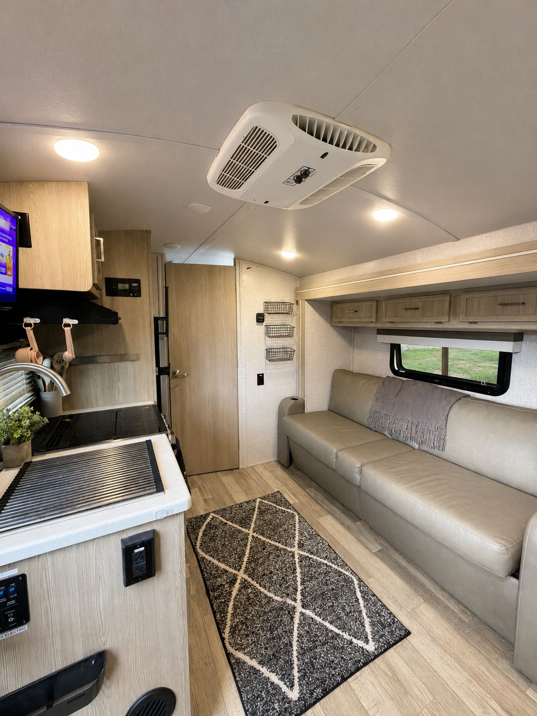 Un intérieur de camping-car compact comprenant un coin cuisine, un espace salon et une fenêtre.