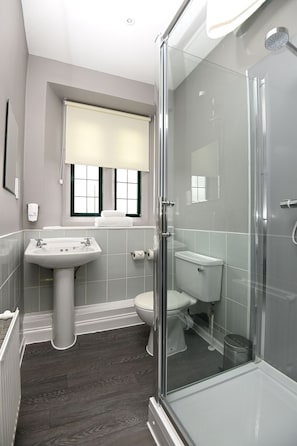 A modern bathroom with a glass shower enclosure, a pedestal sink, and a toilet. - Fox & Goose by Marston's Inns (Bristol)