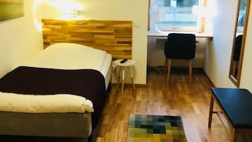 Ett hotellrum med en säng, ett skrivbord, en stol och ett fönster.