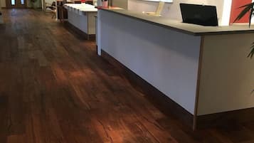 Ett välkomstområde med ett trägolv, en receptionsdisk, en klocka och en vägg prydd med en väggmålning med citrustema.