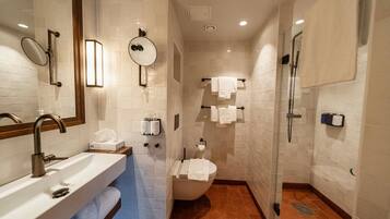 A modern bathroom with a sink, mirror, towel rack, and shower.