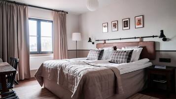 A bedroom with a large bed, a desk, and a window with curtains.