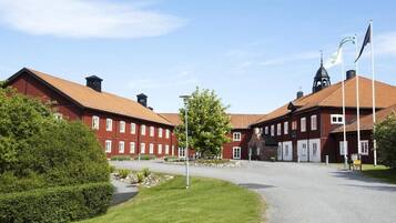 A red brick building with a central courtyard, flagpoles, and a clear sky.
