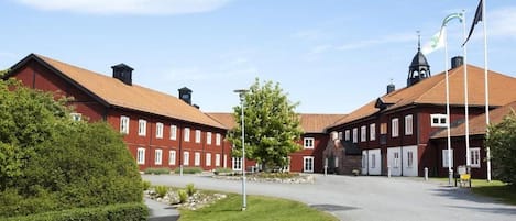 A red brick building with a central courtyard, flagpoles, and a clear sky.