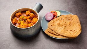 Un plato de curry con pan plano y verduras en rodajas.