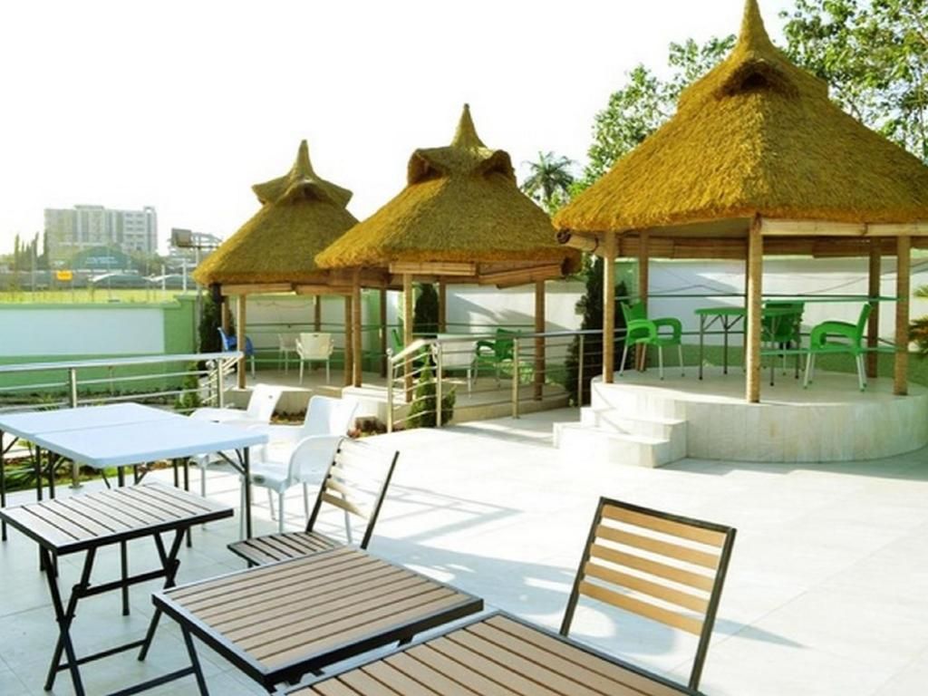 An outdoor seating area with tables and chairs, thatched-roof gazebos, and a view of the city skyline.