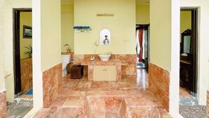 A bathroom with a marble floor, a sink, a toilet, and a cabinet.