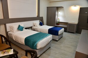 Ein Hotelzimmer mit zwei Betten, einem Schreibtisch und einem Kleiderschrank.