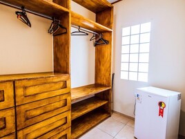 Una habitación con un armario de madera, un refrigerador blanco y una ventana con diseño de cuadrícula.