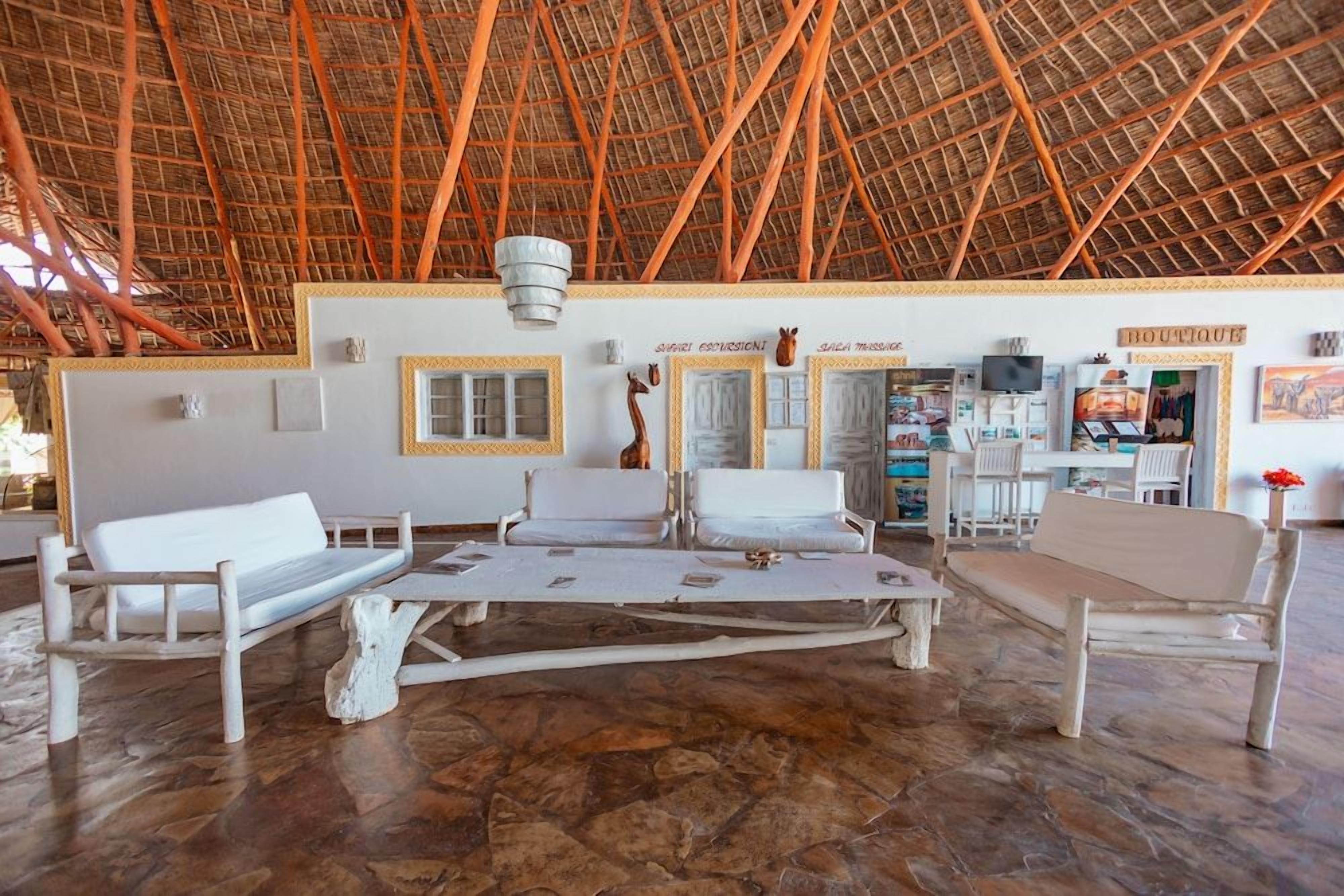 A room with a thatched roof, white furniture, and a stone floor.