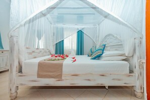 A four-poster canopy bed with a white headboard, a beige bedspread, and blue and white striped pillows. - Twiga Beach Clubviaggi Resort Watamu (Watamu)