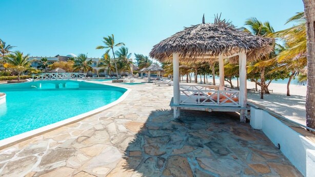 A pool area with a thatched gazebo, palm trees, and a stone pathway. - Twiga Beach Clubviaggi Resort Watamu (Watamu)