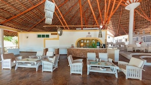 A spacious lounge area with white wicker furniture, a central bar, and a thatched roof ceiling. - Twiga Beach Clubviaggi Resort Watamu (Watamu)