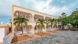 A building with multiple balconies, palm trees, and a stone-paved courtyard. - Twiga Beach Clubviaggi Resort Watamu (Watamu)