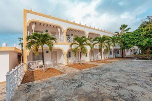 A building with multiple balconies, palm trees, and a stone-paved courtyard. - Twiga Beach Clubviaggi Resort Watamu (Watamu)