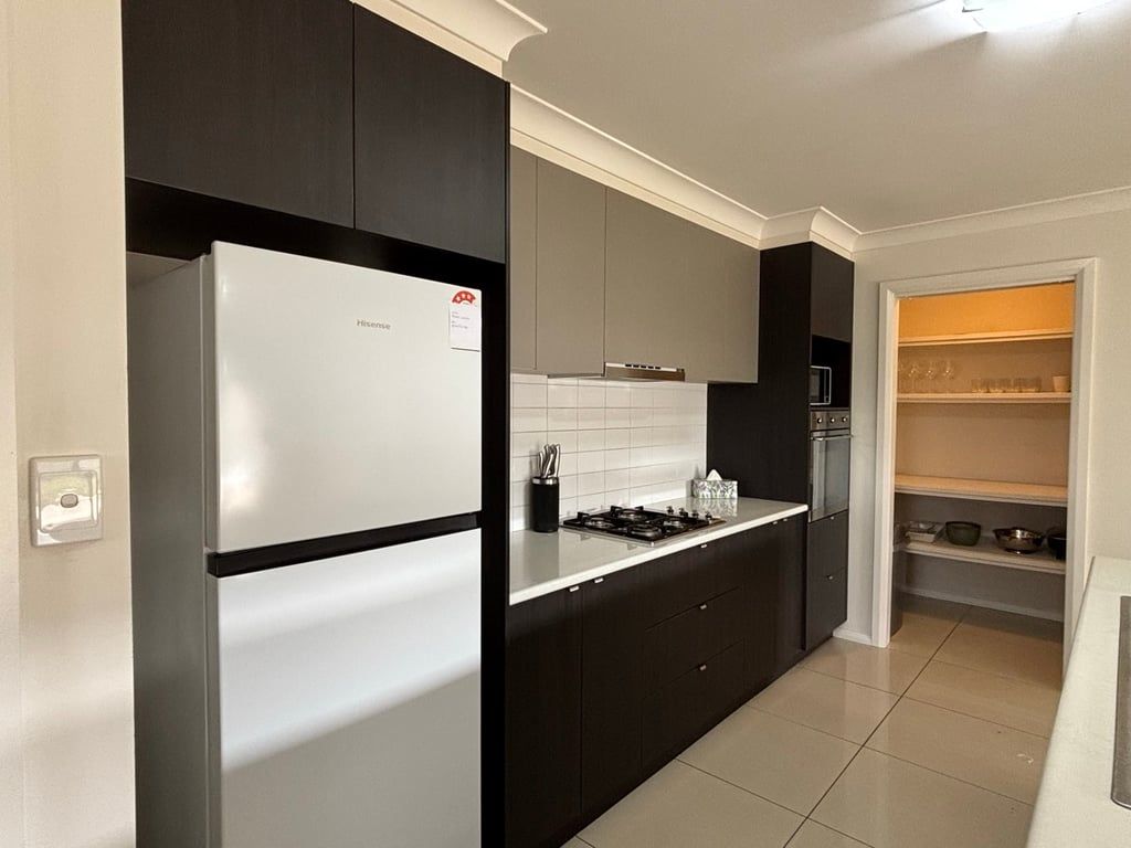 A modern kitchen with dark cabinetry, a white refrigerator, and a gas stove.