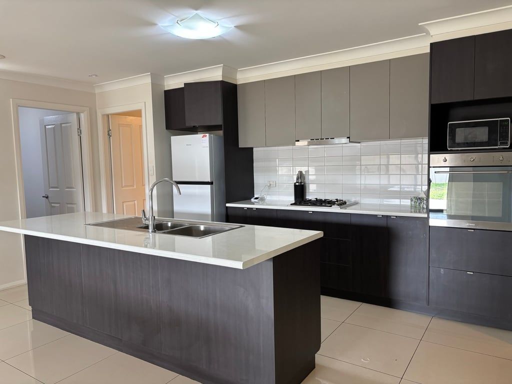 Una cocina moderna con una isla central, electrodomésticos de acero inoxidable y muebles oscuros.