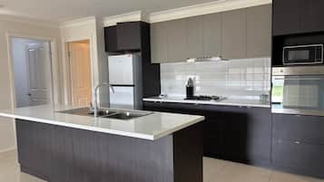 A modern kitchen with a central island, stainless steel appliances, and dark cabinetry.