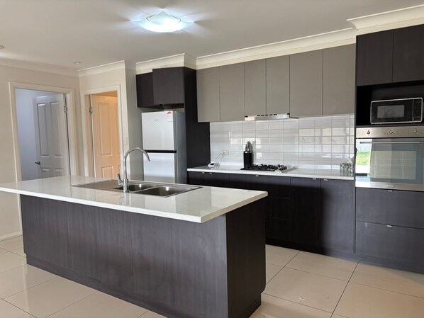 A modern kitchen with a central island, stainless steel appliances, and dark cabinetry.